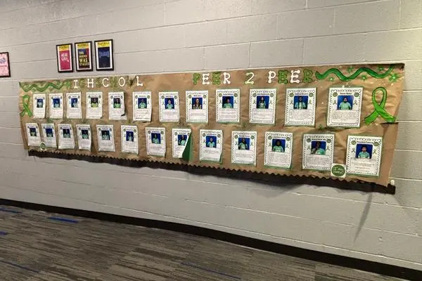 Wide banner displayed in school hallway with P2P student member pictures and why they joined P2P
