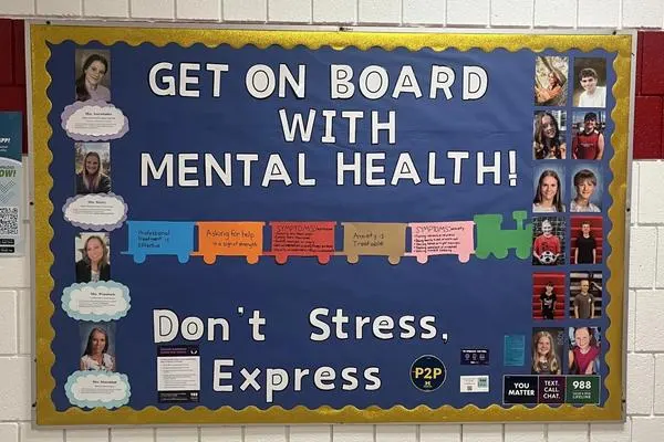 Bulletin board with images of Millington's P2P team and mental health info